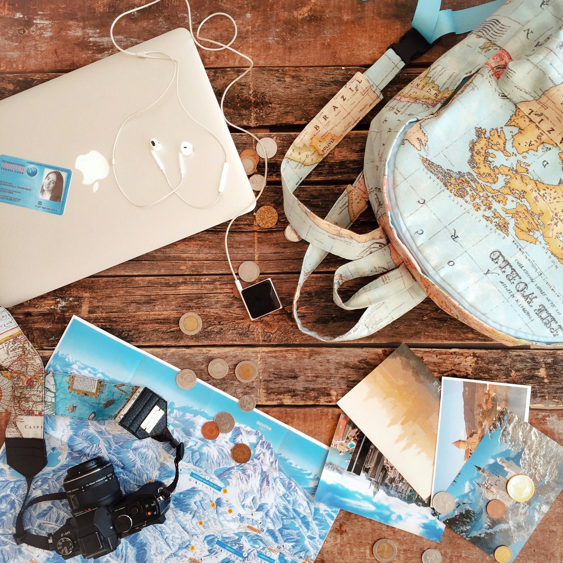 silver macbook beside black dslr camera on brown wooden table